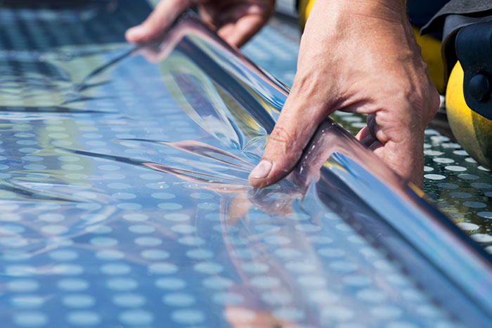 Mitarbeiter rollt UV-Schutzfolie aus.
